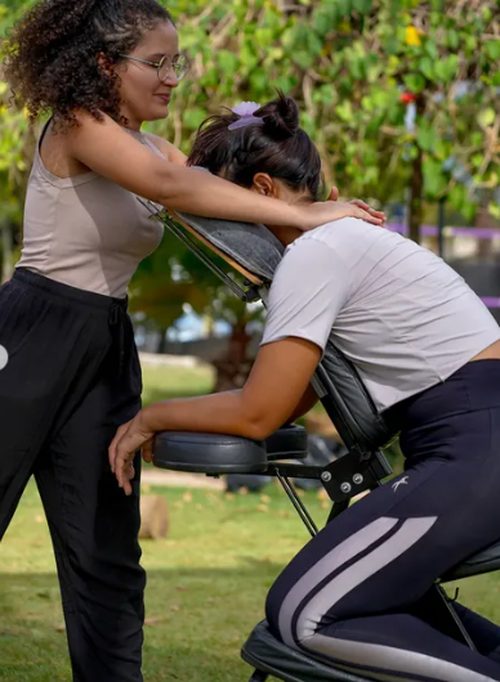 Paloma D'Amdrad aplicando massagem na cadeira ao ar livre em ambiente natural